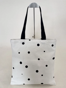 Minimalist white canvas tote bag with black polka dots and black textile straps