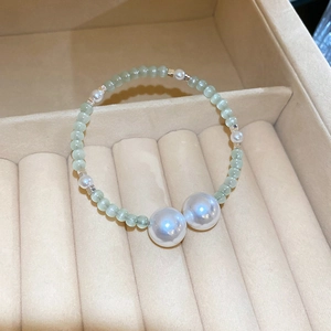 Close-up of elegant beaded bracelet with green glass beads and white pearls in a jewelry box