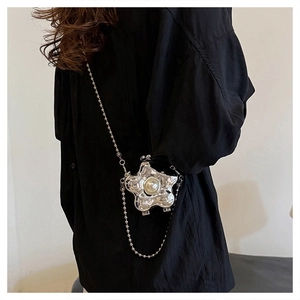 Détail du mini sac bandoulière argenté en forme d'étoile avec perles sur le mannequin