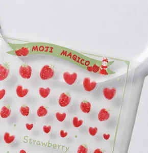 Close-up macro detail of strawberry and heart nail art stickers with matte texture.