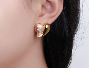 Macro view of gold-plated heart earring with cubic zirconia pavé and polished finish