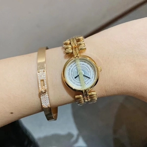 Close-up of a gold quartz watch and matching luxury studded bracelet on a wrist