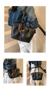 Close-up of black pleated tote bag with chocolate and cat charms on a model