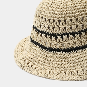Close-up of woven straw hat featuring intricate crochet texture and black stripes