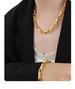 Close-up of a gold chunky link chain necklace and bracelet set on a stylish model