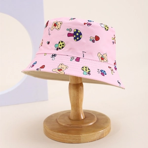 Detail of pink cotton bucket hat with cute bear and mushroom prints on a wooden stand
