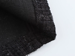 Gros plan sur le tissu en tweed noir montrant une texture tissée et sequins scintillants