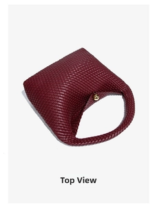 Top view of burgundy woven handbag with elegant gold metal sphere clasp and minimalist texture