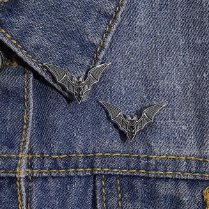 Detail of bat-shaped enamel pins on denim collar for Halloween dark style fashion