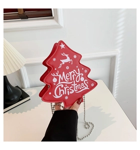 Détail d'un sac à bandoulière rouge en forme de sapin de Noël avec motifs de rennes et de flocons