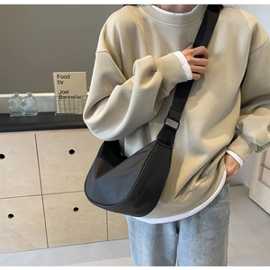 Detail of black crossbody crescent bag with adjustable strap worn on a casual outfit