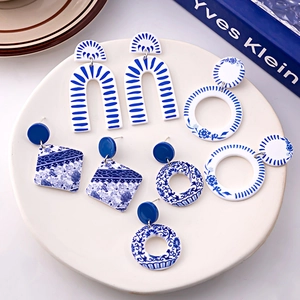 Blue and white porcelain style earrings in geometric shapes displayed on a ceramic tray