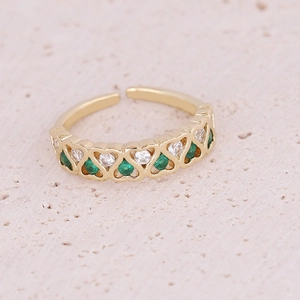 Macro detail of gold-plated open ring with heart patterns and green zircon inlay