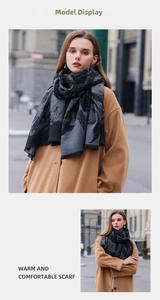 Detail of grey and black patterned knit scarf with tassels paired with a camel wool coat