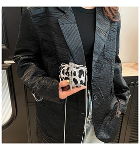 Mini cow print crossbody bag with silver chain strap worn with a stylish black blazer