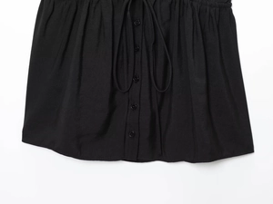 Vue détaillée du haut plissé noir boutonné avec ruban de serrage délicat à la taille