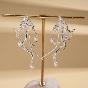Detail shot of silver branch pearl earrings on a display stand showing metallic texture