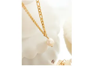 Macro detail of gold double-layered necklace with freshwater pearl and Figaro chain