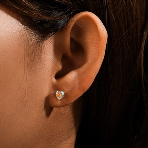 Close-up of heart-shaped moonstone stud earring in gold finish on female model ear