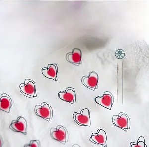 Detailed macro view of 5D embossed heart pattern nail stickers on white fabric