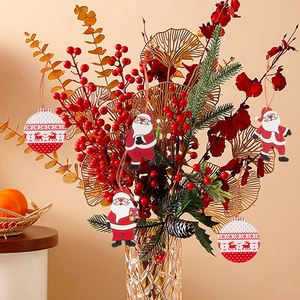 Christmas gnomes and red ornaments hanging on a festive pine branch in a glass vase