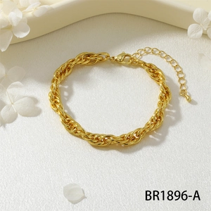 Dettaglio di un bracciale dorato a maglie con chiusura a moschettone su seta bianca e fiori