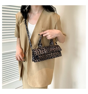 Close-up of leopard print handbag with detachable shoulder strap worn by a model