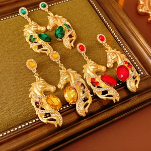 Detailansicht von Vintage-Pferdekopf-Ohrringen mit bunten Kristallen auf grünem Samt