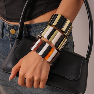 Detailed close-up of acrylic geometric stretch bracelets in gold and tortoiseshell patterns