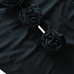 Détails macro des fleurs de roses 3D en tissu sur une robe noire moulante élégante