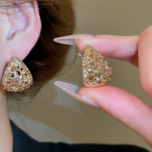 Close-up of champagne crystal teardrop earrings with a hollow gold-tone metal frame