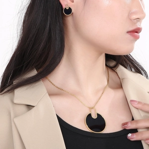 Close-up of elegant gold necklace and black round earring set worn by a model