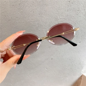 Détail de lunettes de soleil ovales sans monture avec branches dorées et verres dégradés