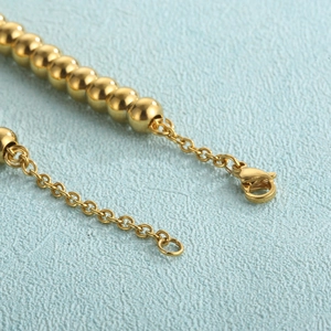Macro detail of 18K gold plated beaded bracelet showing lobster clasp and extender chain