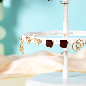 Close-up of a white rotating jewelry organizer rack with hanging earrings detail