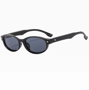 Détail de lunettes de soleil ovales noir mat avec rivets en métal et verres gris