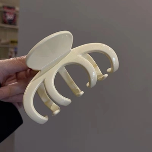 Detailed close-up of cream-colored large claw clip with smooth polished finish held in hand