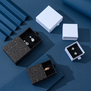 Dettaglio di scatole portagioie a cassetto bianco e nero con texture dorata e nastro