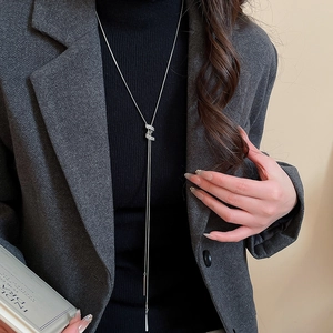 Macro shot of silver adjustable spiral necklace with zircon tassel on black turtleneck