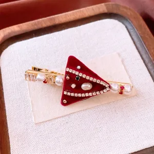 Festive red velvet triangular hair clip with pearls and gemstones on a display card