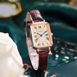 Detail of rectangular rose gold quartz watch with blue hands and brown leather strap