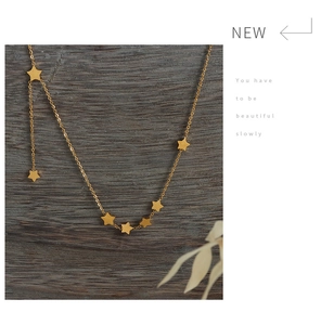 Detail of gold star charm necklace with seven star pendants on dark wood texture