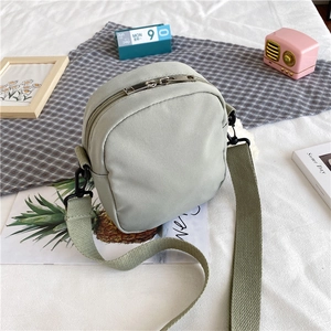 Vue détaillée d'un petit sac bandoulière en nylon vert pâle avec double fermeture éclair