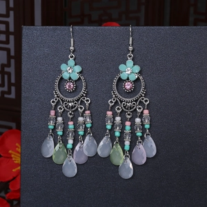 Dettaglio di orecchini boho con fiori turchesi e nappe di perline colorate pendenti