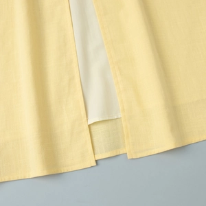 Détail de l'ourlet de la jupe en lin jaune pâle avec fente latérale et doublure blanche