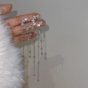 Close-up of silver tassel earrings with sparkling zircon leaves and white pearl accents