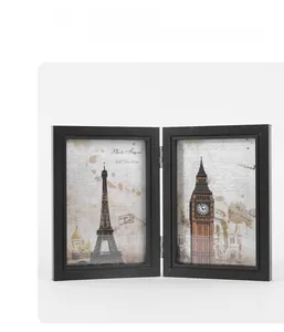 Detail of a black folding double picture frame with metallic hinges and city art prints