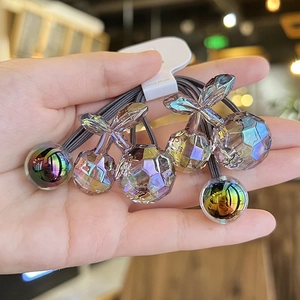 Close-up of translucent cherry hair ties with iridescent finish on a handmade card