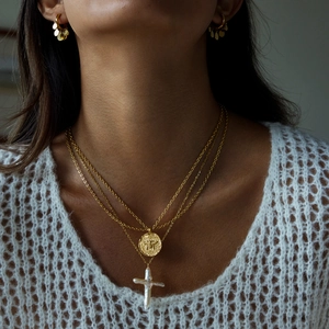 Detail of 18K gold coin bee pendant and pearl cross necklace on model neck