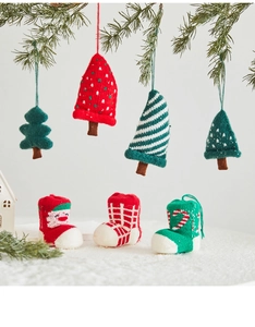 Close-up of handmade knitted Christmas tree ornaments and stockings on pine branches